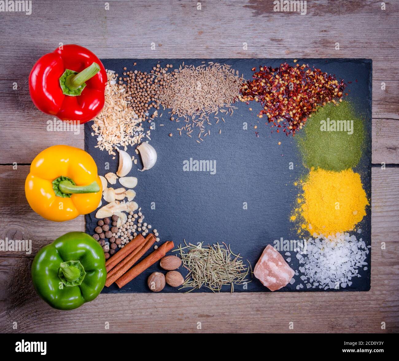 Spices, herbs and fresh pepper on slate tray on an old rustic table. Red, yellow and green fresh peppers. Top view. Rustic style. Fresh ingredients an Stock Photo