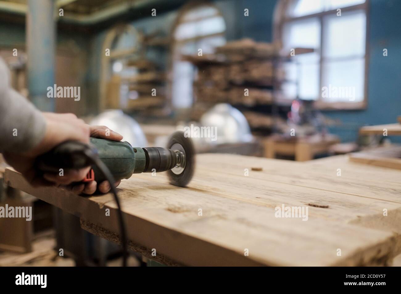 Hand working with a brushing machine sanding a piece of wood. Stock Photo