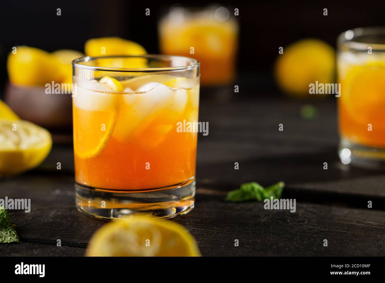 Cold drink of lemon iced tea on dark background. A refreshing summer drink made of fresh hand squeezed lemon mixed with cold black tea, ice and sugar. Stock Photo