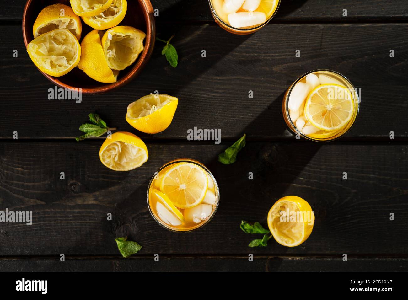 Lemon iced tea from above on dark background. A refreshing summer drink made of fresh hand squeezed lemon mixed with cold black tea, ice and sugar. Ad Stock Photo