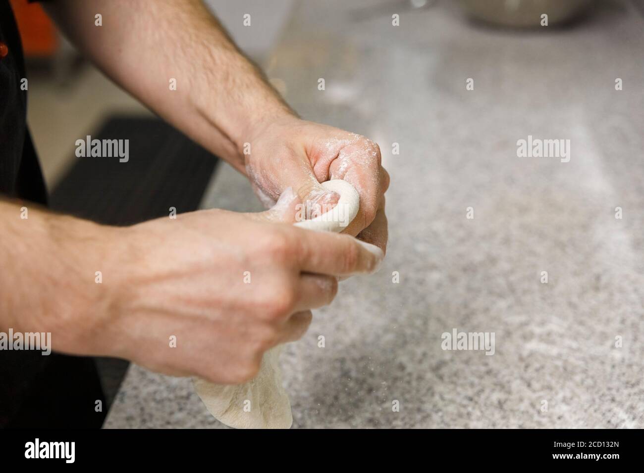 Making dough by male hands on table background.  Pizza maker prepares a pizza dough. Stock Photo