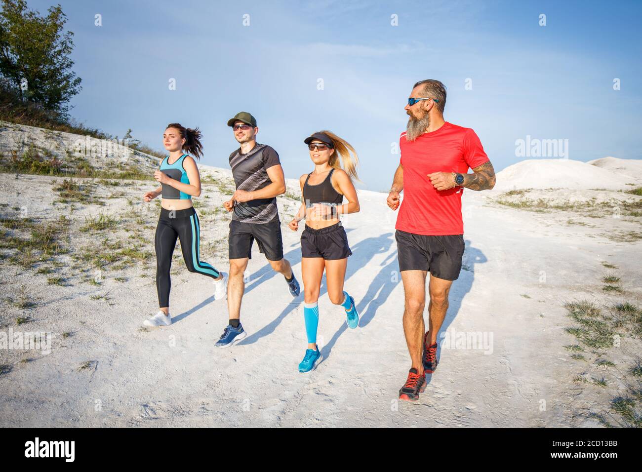 Group of runners jogging outdoors on white terrain. Low wide angle view with long shadows Stock Photo