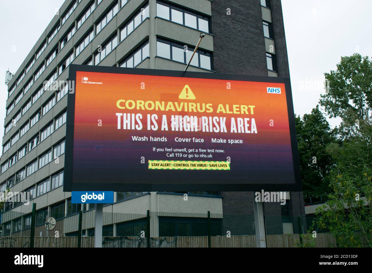 Electronic billboard with warning This is a High Risk Area on entry into Greater Manchester from A6. Office and residential building in UK. Stock Photo