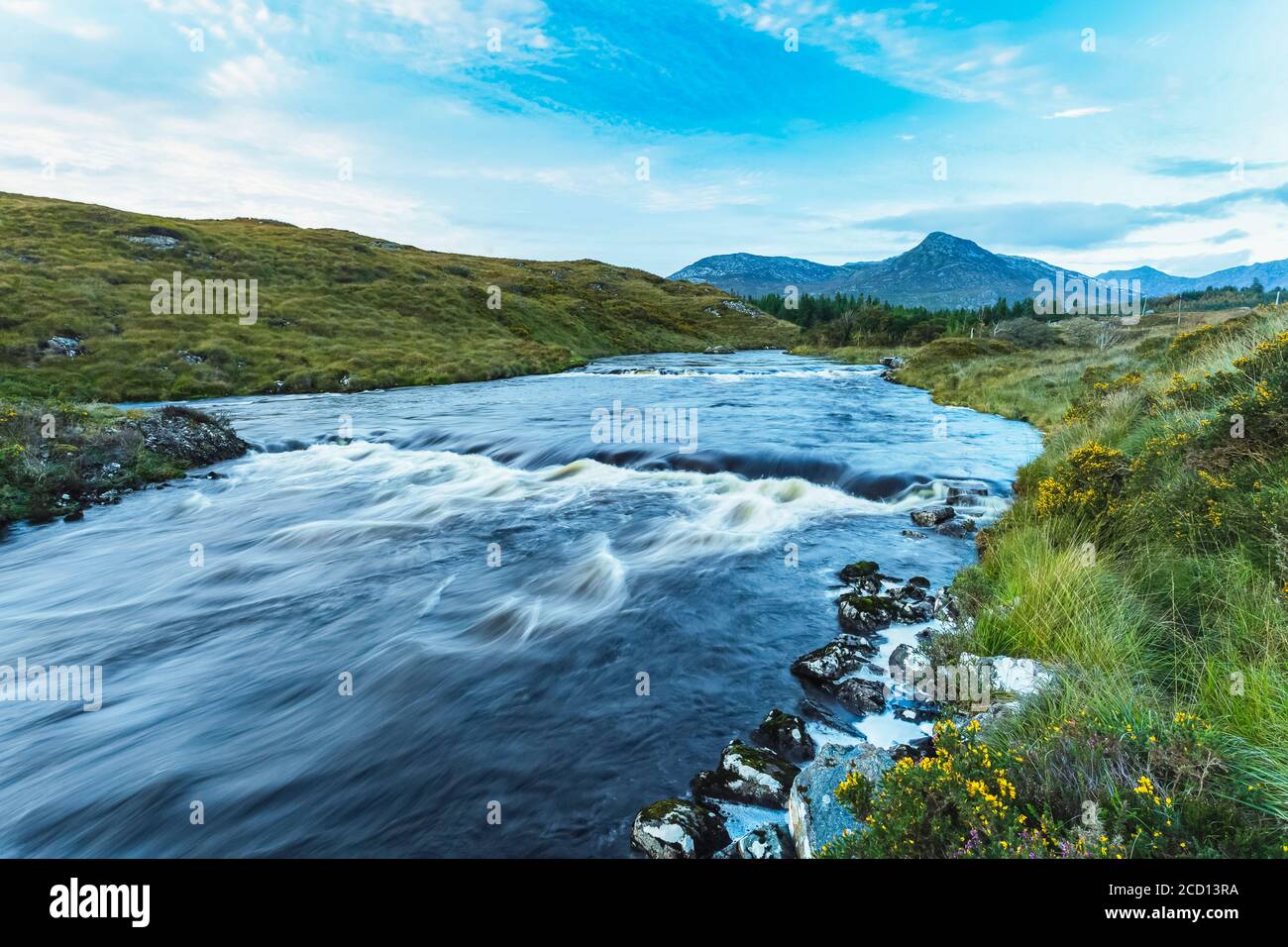 Small rapids on a river flowing through Connemara with a mountain in the background on a blue sky day; Connemara, County Galway, Ireland Stock Photo