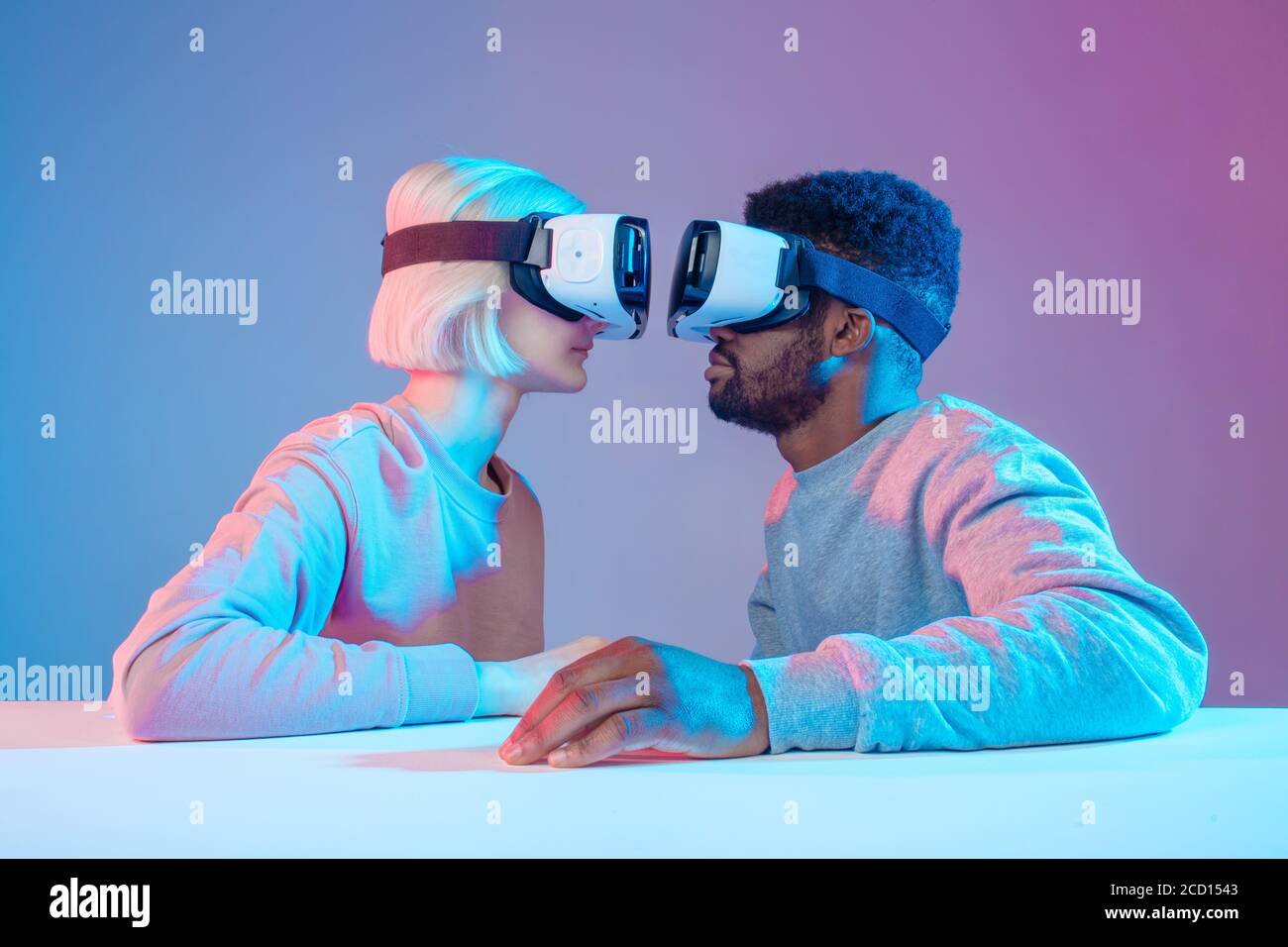 two funny people sitting in front of each other and using virtual reality  goggles,playful couple in VR glasses looking at each other, close up side  vi Stock Photo - Alamy