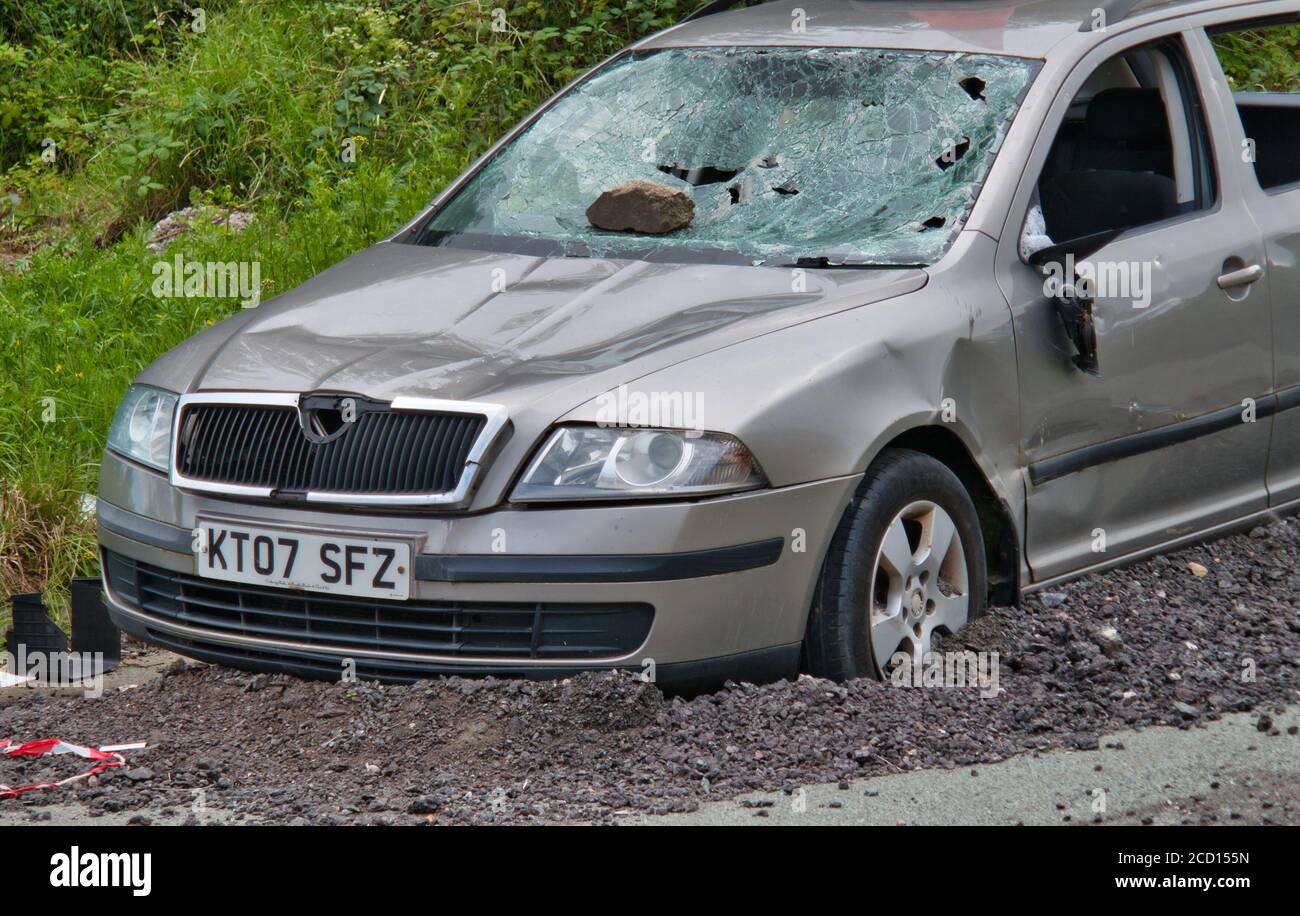 An abandoned, vandalised car, with smashed windscreen and missing windows Stock Photo