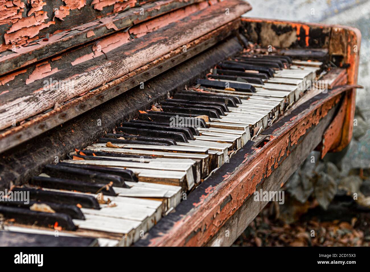 An old broken piano thrown into the street with peeling paint and leaves on  the keys. Selective focus Stock Photo - Alamy