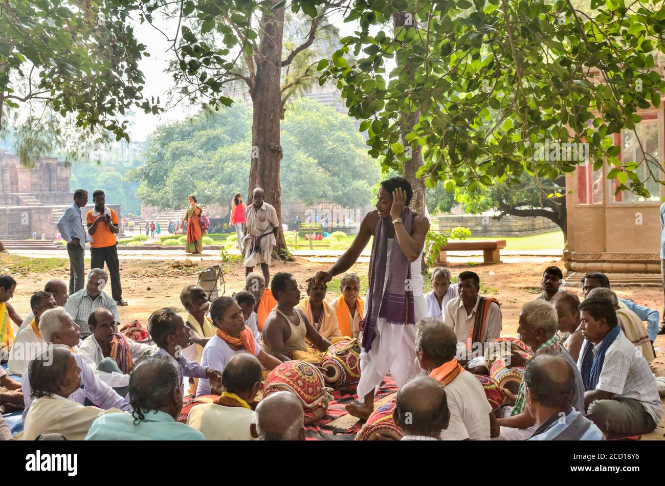 Gathering of men and musicians around a male singer under trees near a temple, Konark Sun Temple; Odisha State, India Stock Photo