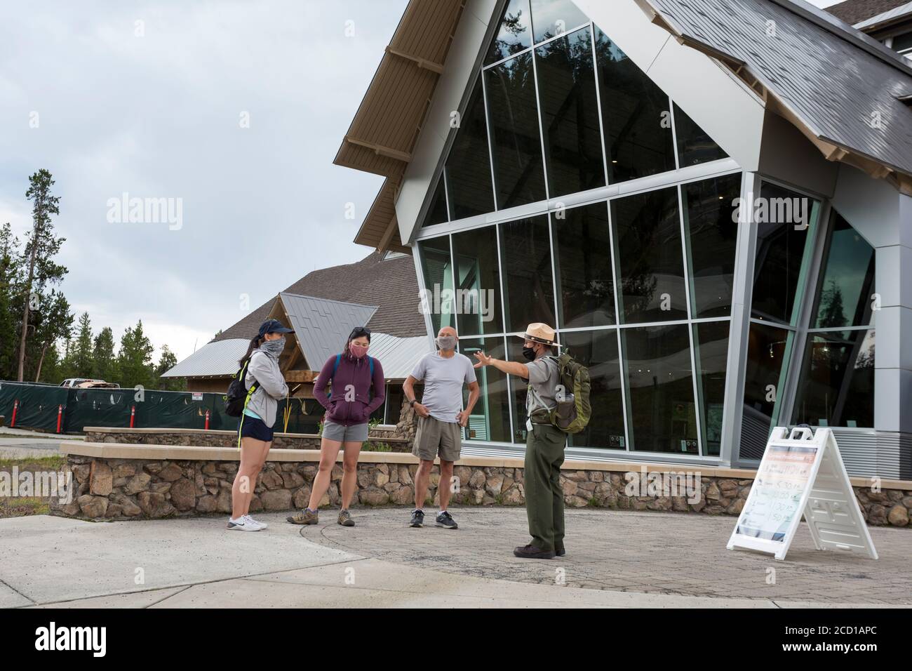 A National Park Ranger advises visitors outside the closed The Old Faithful Visitor Education Center in Yellowstone National Park, Wyoming on Monday, Stock Photo