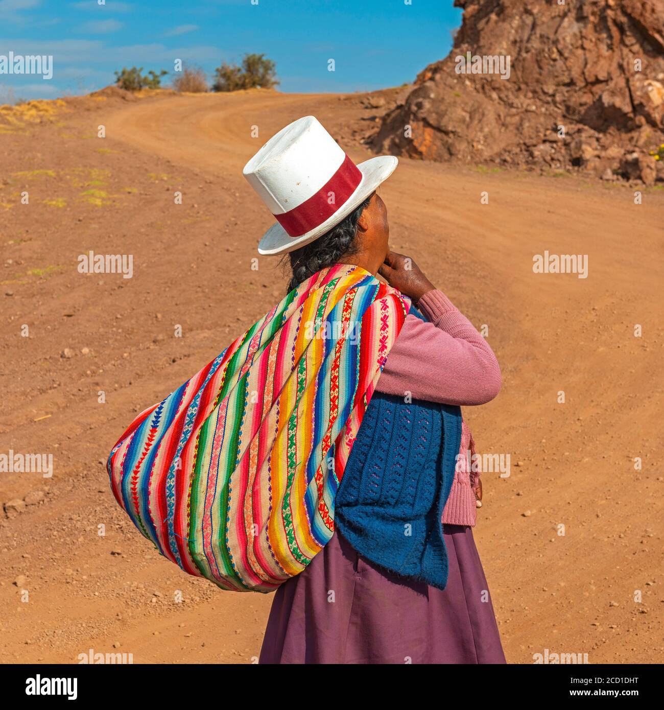 Indigenous peruvian Quechua woman with traditional hat and textile along a Andes road, Sacred Valley of the Inca, Cusco, Peru. Stock Photo
