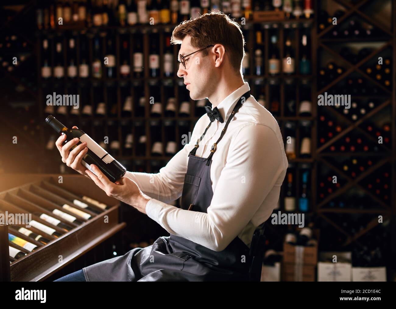 Elegant wine seller holding a bottle of wine and reading label in a