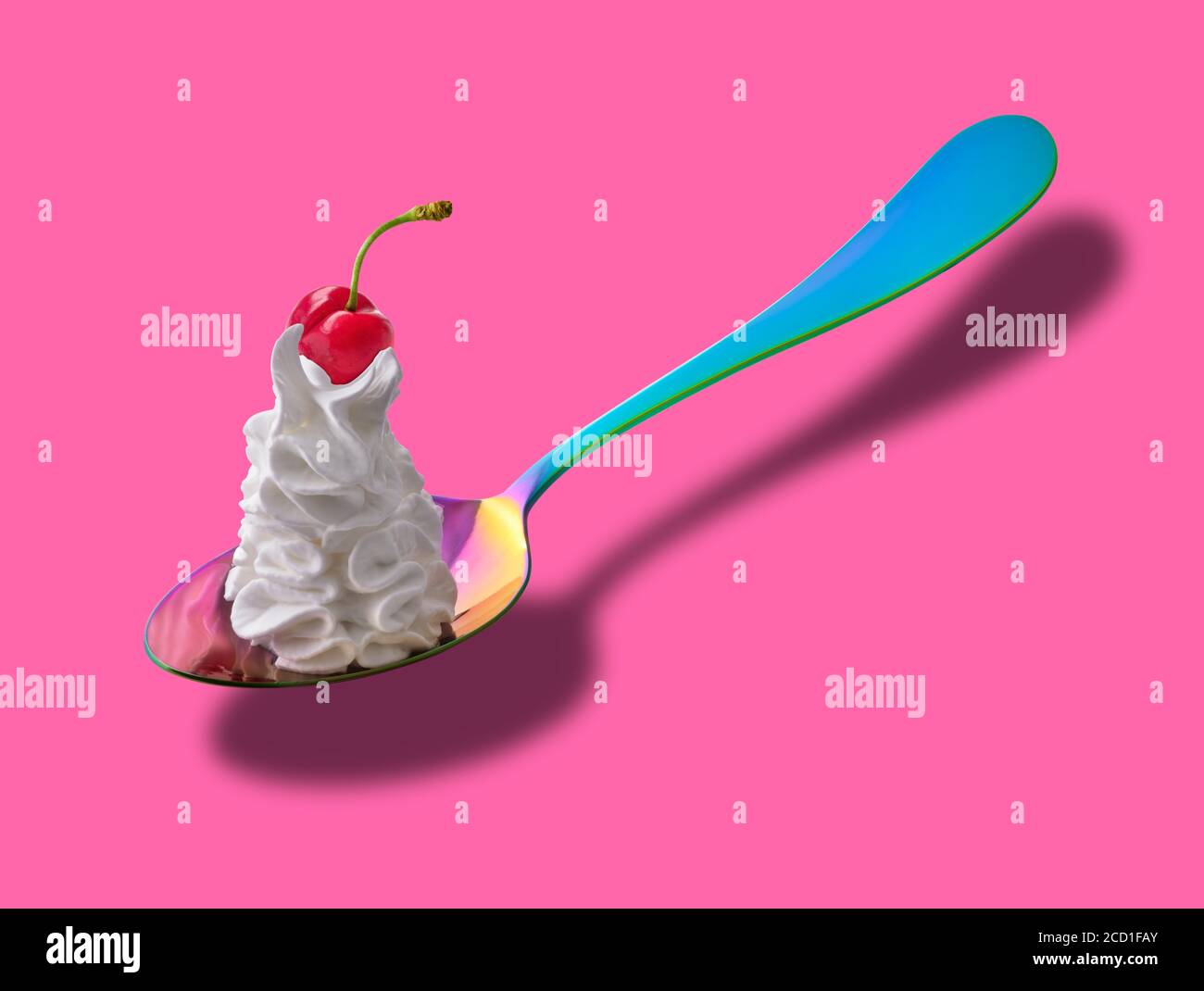 Colorful spoon with whipped cream and a cherry on top Stock Photo