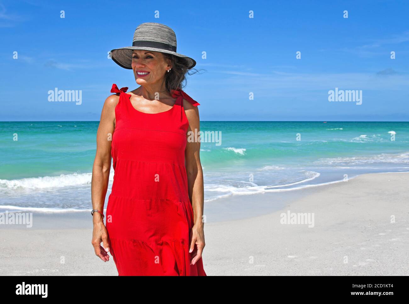 Beautiful Mature Woman Wearing a Red Summer Dress on the Beach Stock Photo