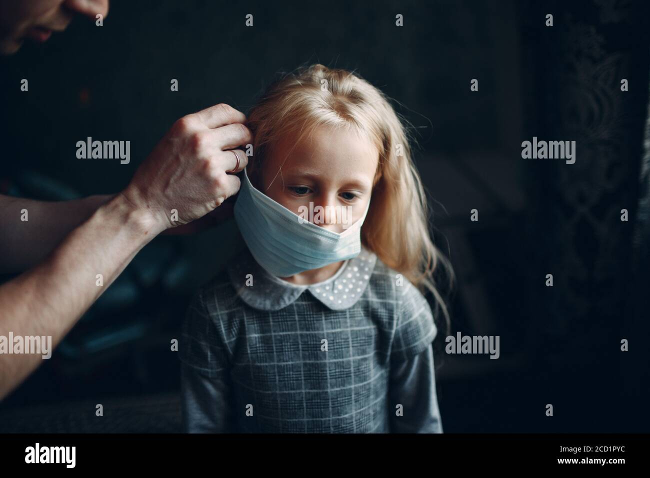 Parent helping daughter dressing uniform and put face mask preparation