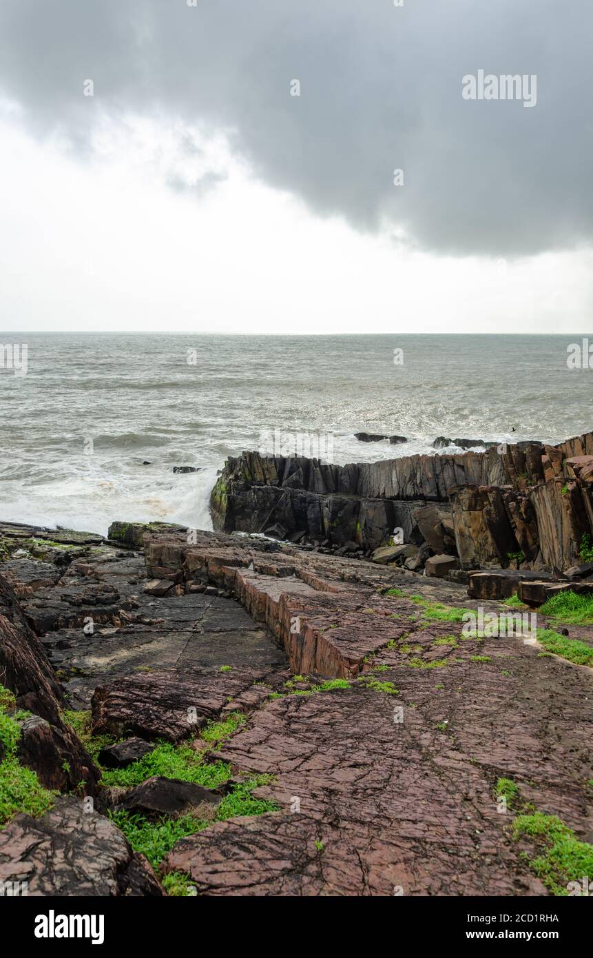 Monsoon Season view of the rough Arabian Sea and Rocky Shoreline near Lower Aguada or also called Devil's Finger, Sinquerim, Goa, India Stock Photo