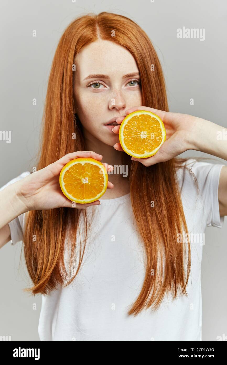 ginger girl with beautiful green eyes posing with fruit. close up vertical shot. skin