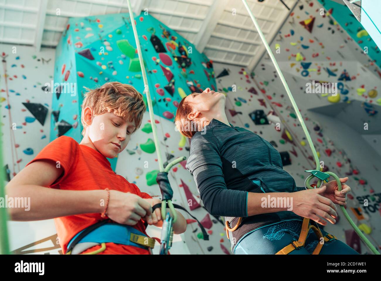 Mother and teenage son at indoor climbing gym near climbing wall