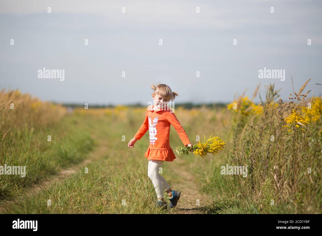Cute little girl dancing and holding a bouquet of wildflowers Stock ...
