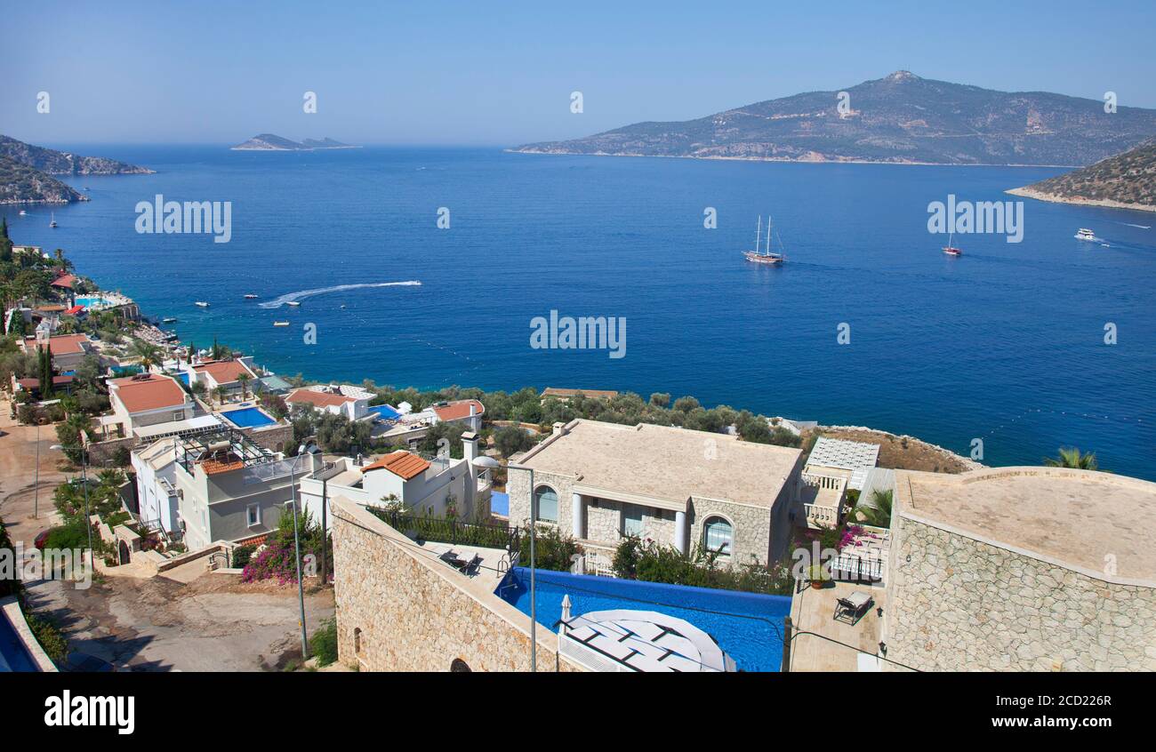 Villas overlooking  the sea in Kormuluk which is part of  Kalkan, Turkey. Charter boats can be seen sailing in the Kalkan bay located on the Turkish M Stock Photo