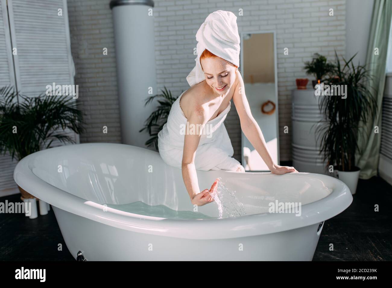 Beautiful woman in bath wear is going to wash her body in the bathtub ...