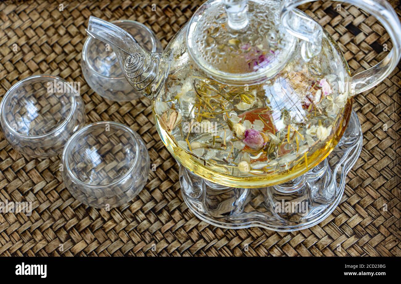 Herbal tea of drying flowers, close up. A teapot and cup with flowers tea on table. Stock Photo