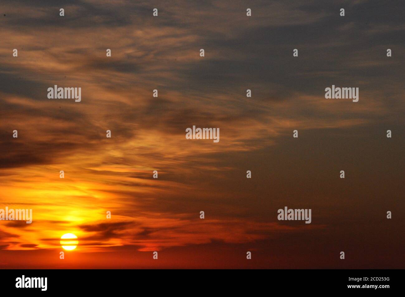 Beautiful sunset sky background with clouds hiding sun Stock Photo