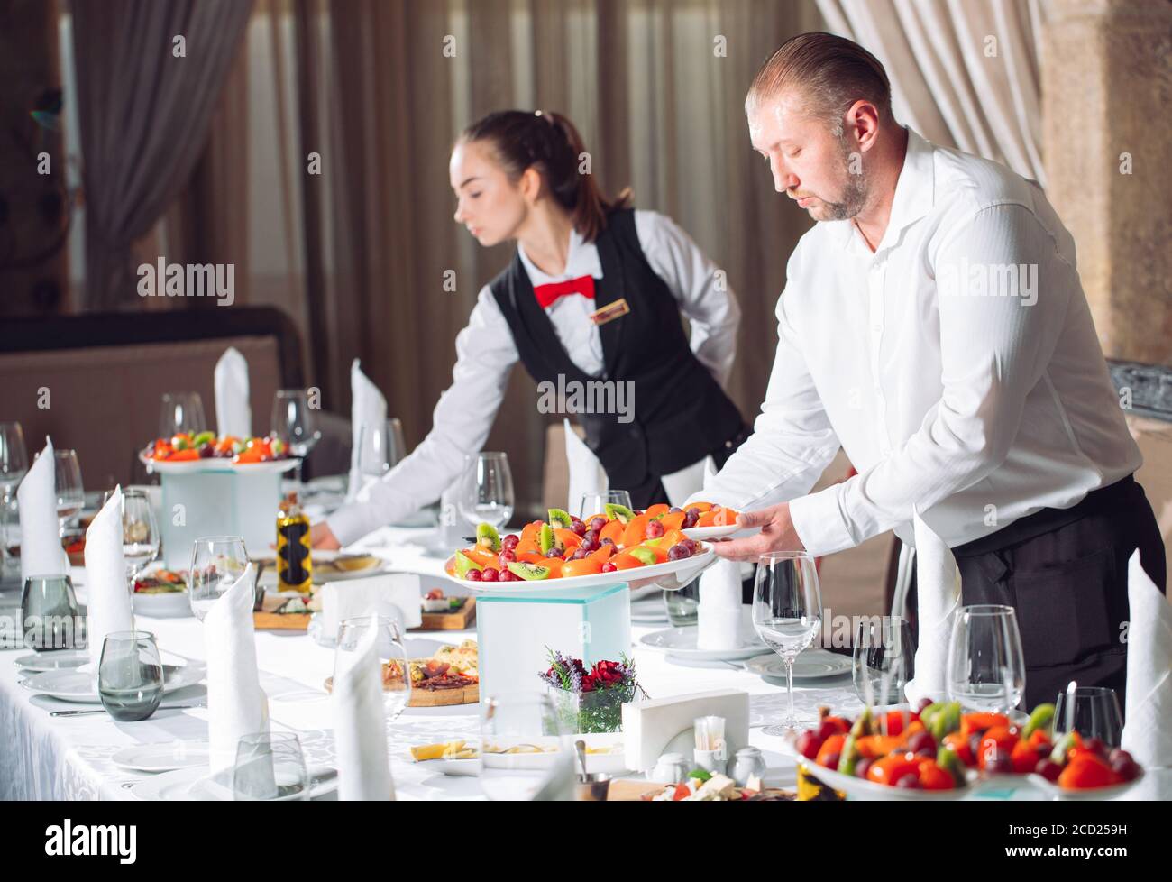 Waiters serving table in the restaurant preparing to receive guests