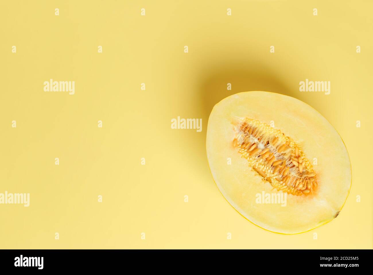 Half of yellow ripe sweet honeydew melon over yellow background. Vegetarian, raw food diet and healthy eating concept. Sweet fruits. Copy space. Stock Photo