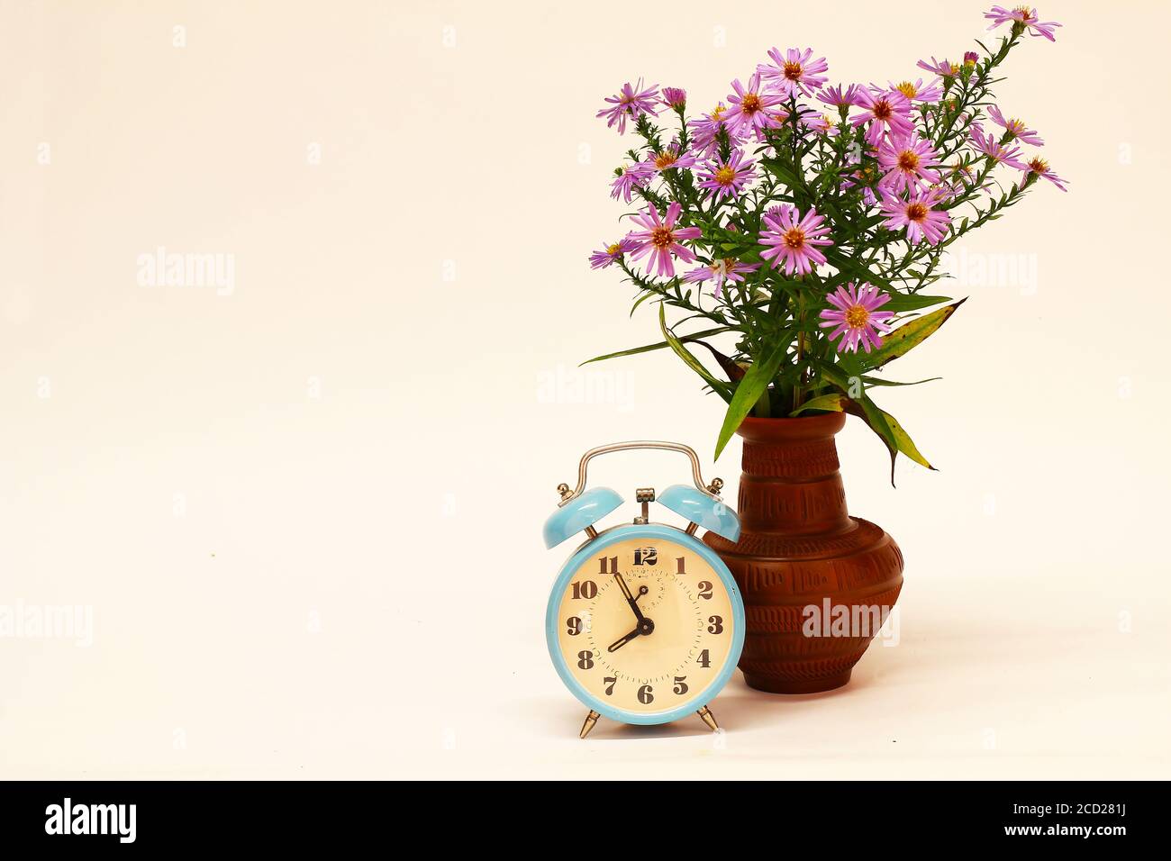 Alarm clock and a vase with flowers on white background Stock Photo - Alamy
