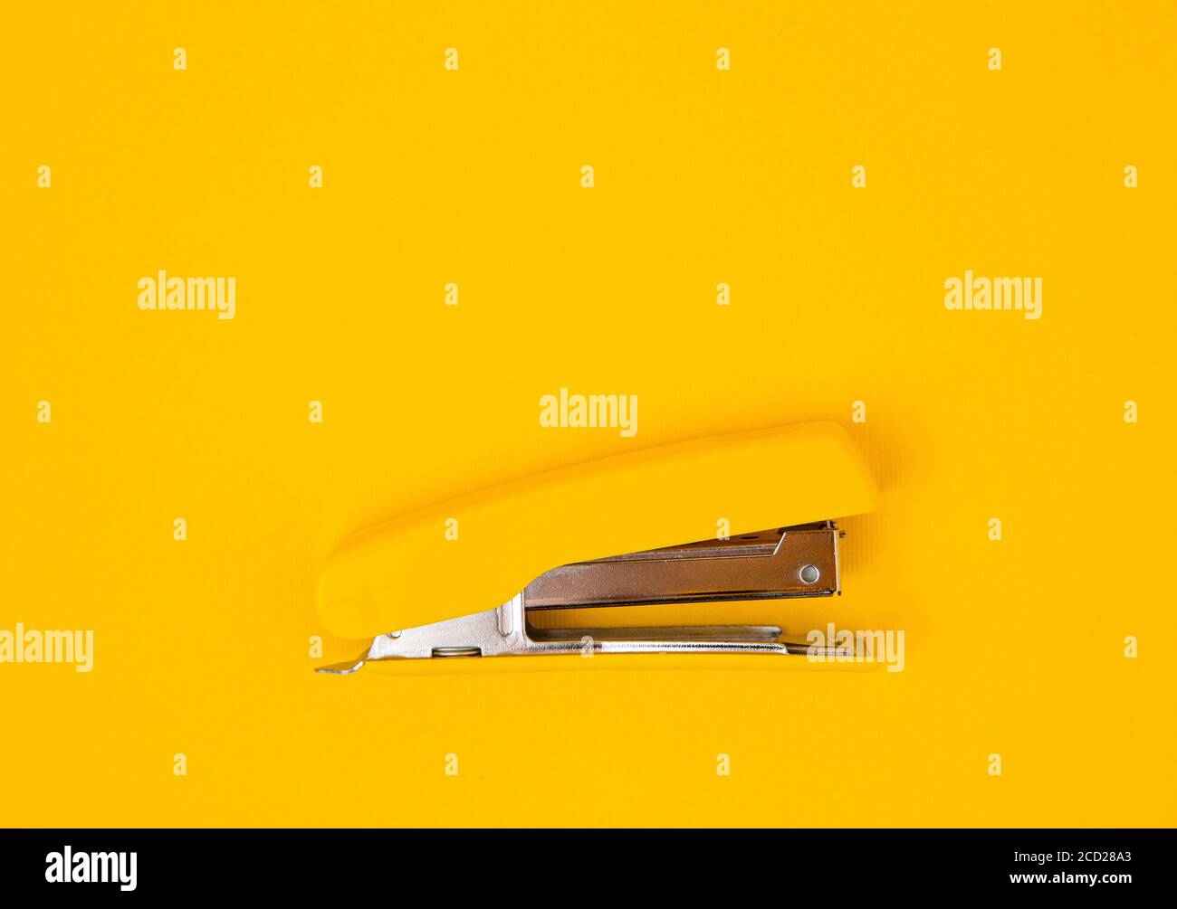 Yellow stapler on yellow background. Top view. Copy, empty space for text. Minimalistic concept Stock Photo