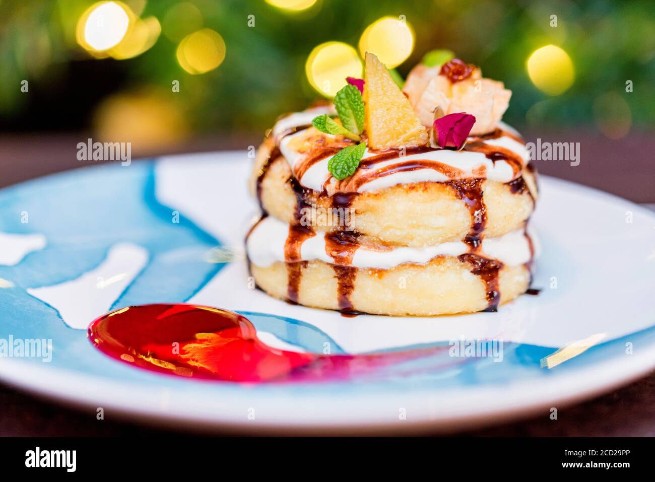 Cottage cheese pancakes or syrniki with cream, fruit jam and flower decoration Stock Photo