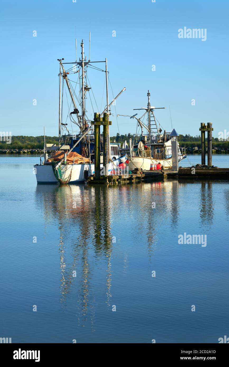 Fishboats at Dock. Calm water and clear sky over the harbor of Steveston, British Columbia, Canada near Vancouver. Steveston is a small fishing villag Stock Photo