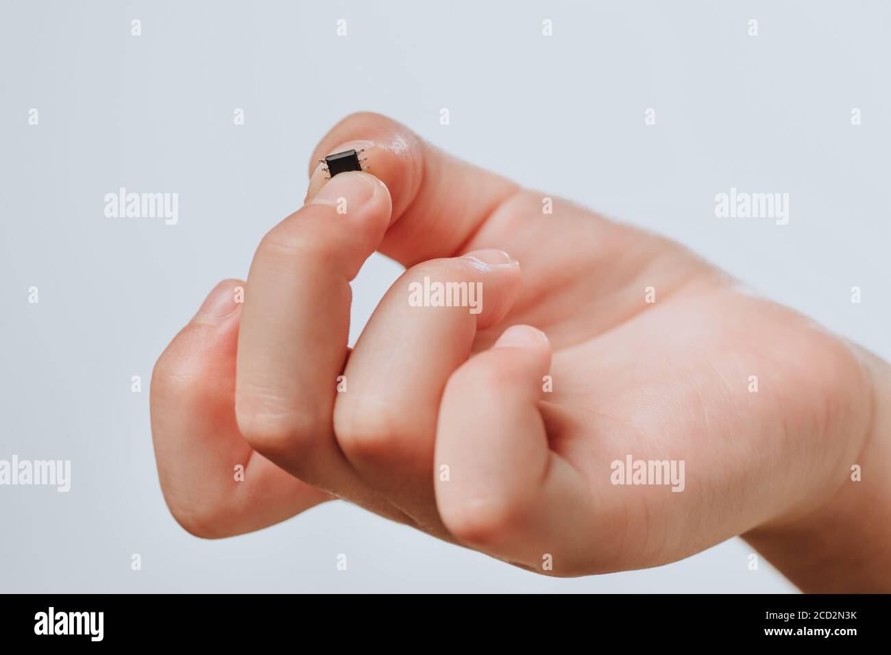 A small black chip holds a children's hand. Chipization of people after an epidemic coronavirus.  Stock Photo