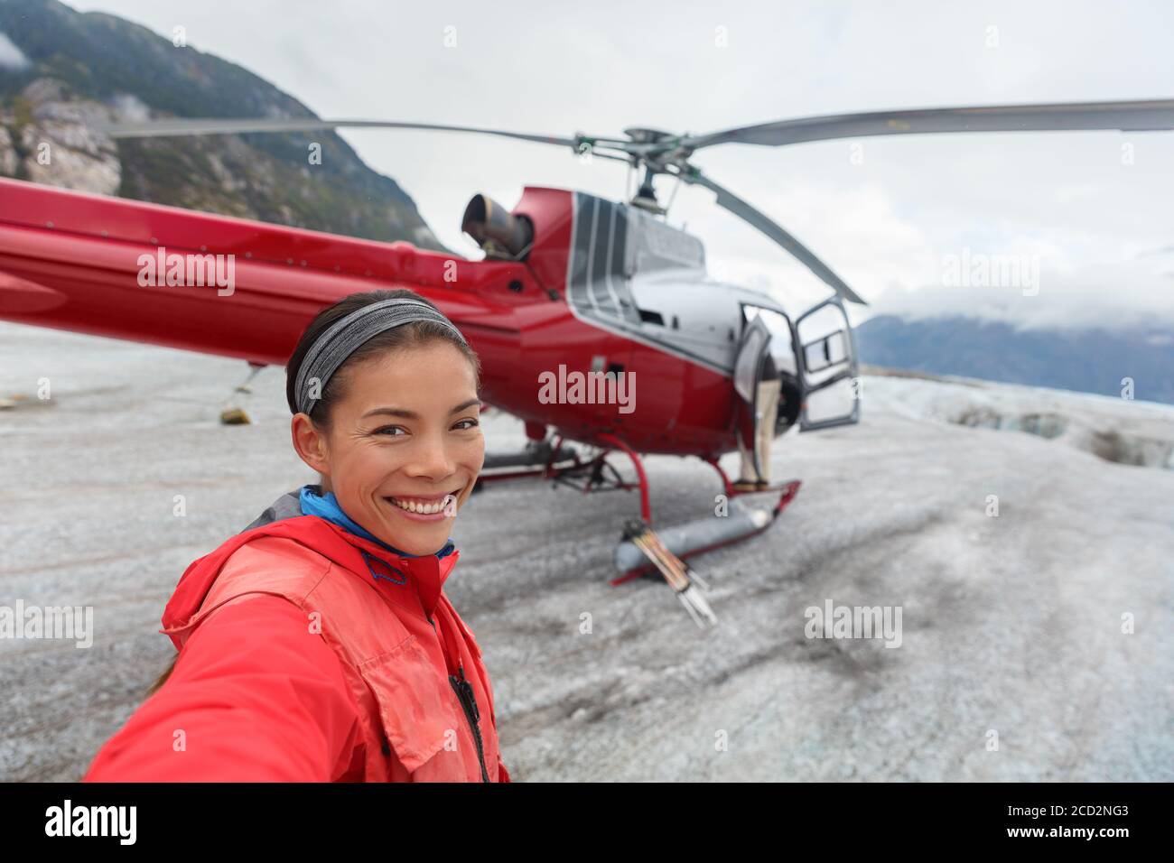 Happy tourist taking selfie picture on helicopter tour excursion. Asian woman cruise passenger on shore activity glacier walk hike in Alaska, USA. Stock Photo