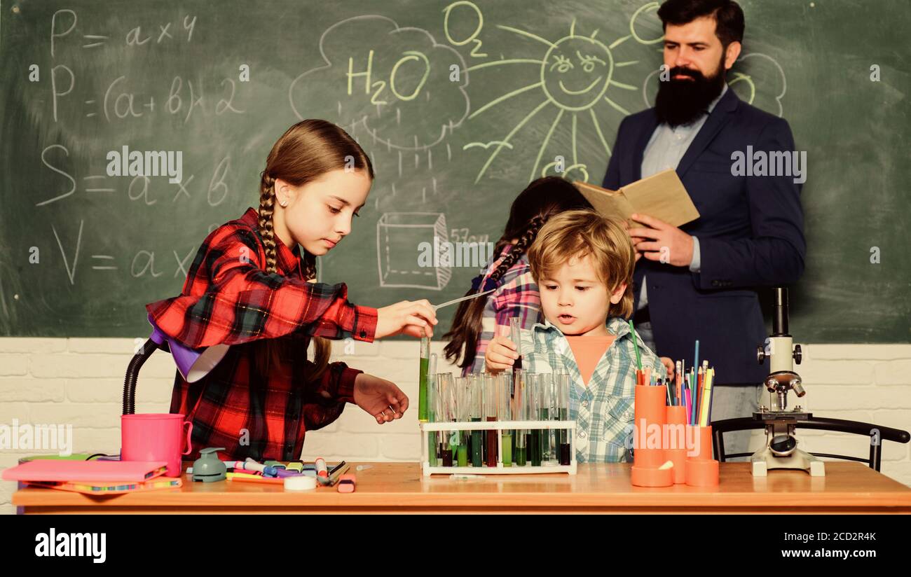 doing experiments with liquids in chemistry lab. chemistry lab. happy children teacher. back to school. kids in lab coat learning chemistry in school laboratory. Confident doctors team. Stock Photo