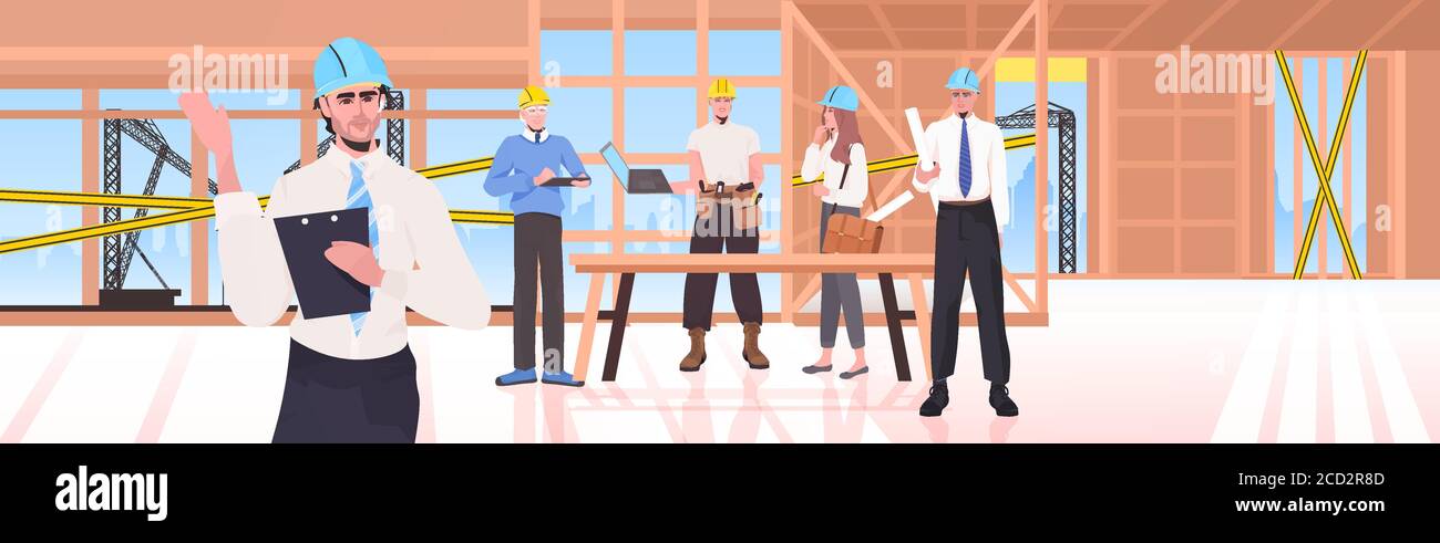 builders team at construction site engineers in helmets discussing ...