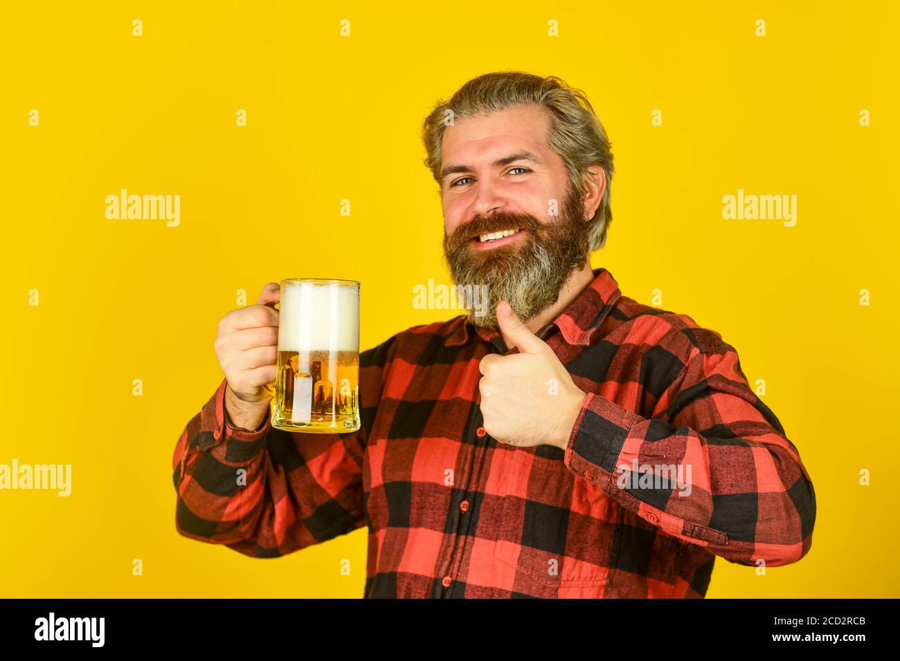 confident bartender raising toast. leisure and celebration. Man drinking beer in pub bar. Beer with foam. brutal hipster drink beer. mature bearded barman hold beer glass. take tasting notes. Stock Photo