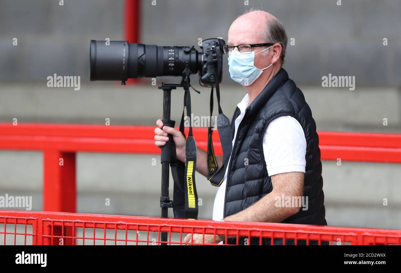 Sports Photographer Simon Dack at work during the Coronavirus pandemic wearing a face mask at  Crawley Town v Crystal Palace at the People’s Pension Stadium. Credit: James Boardman Stock Photo
