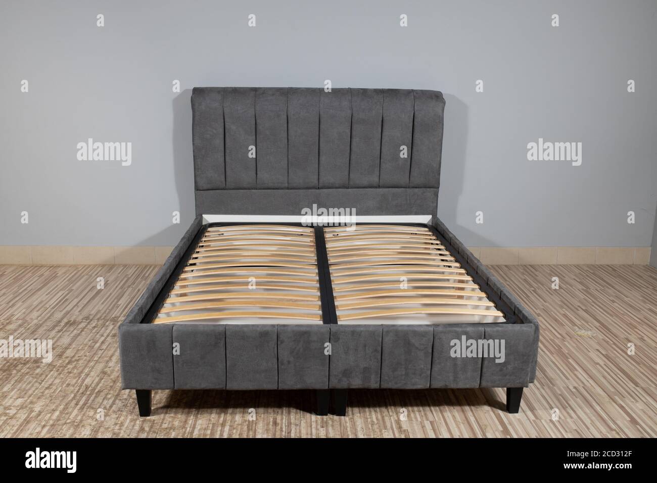 Bed with gray upholstery without mattress in an empty room Stock Photo