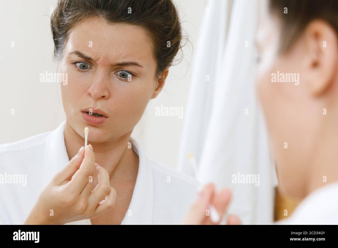 Woman cleansing her ears with a cotton swab in the bathroom Stock Photo