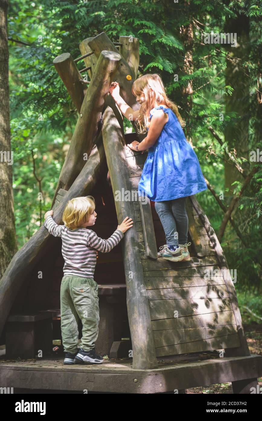 Kids playing outside at a play area with wooden toy house Stock Photo