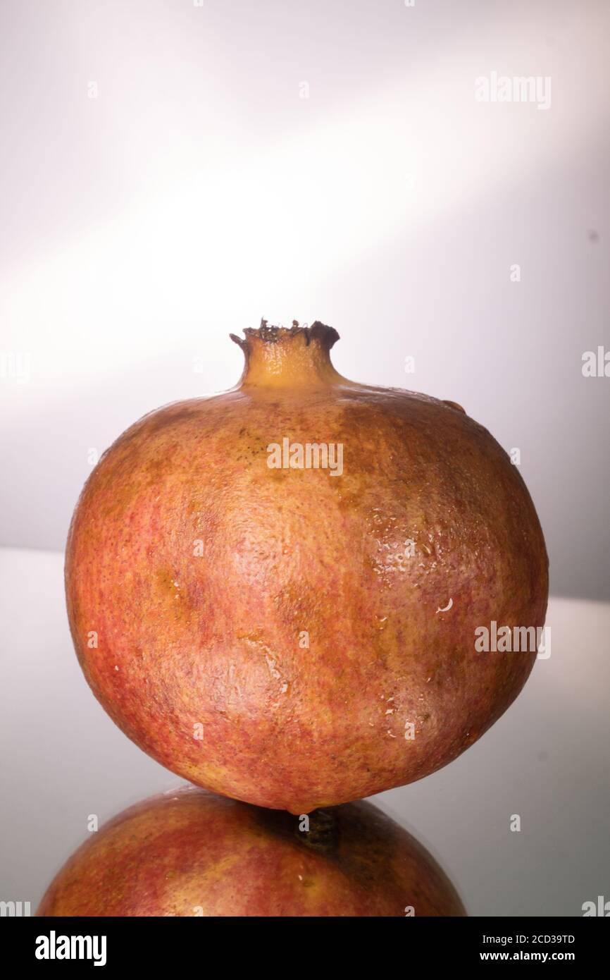 Red pomegranate on mirroring table. Gorizontal image with copy space. Stock Photo