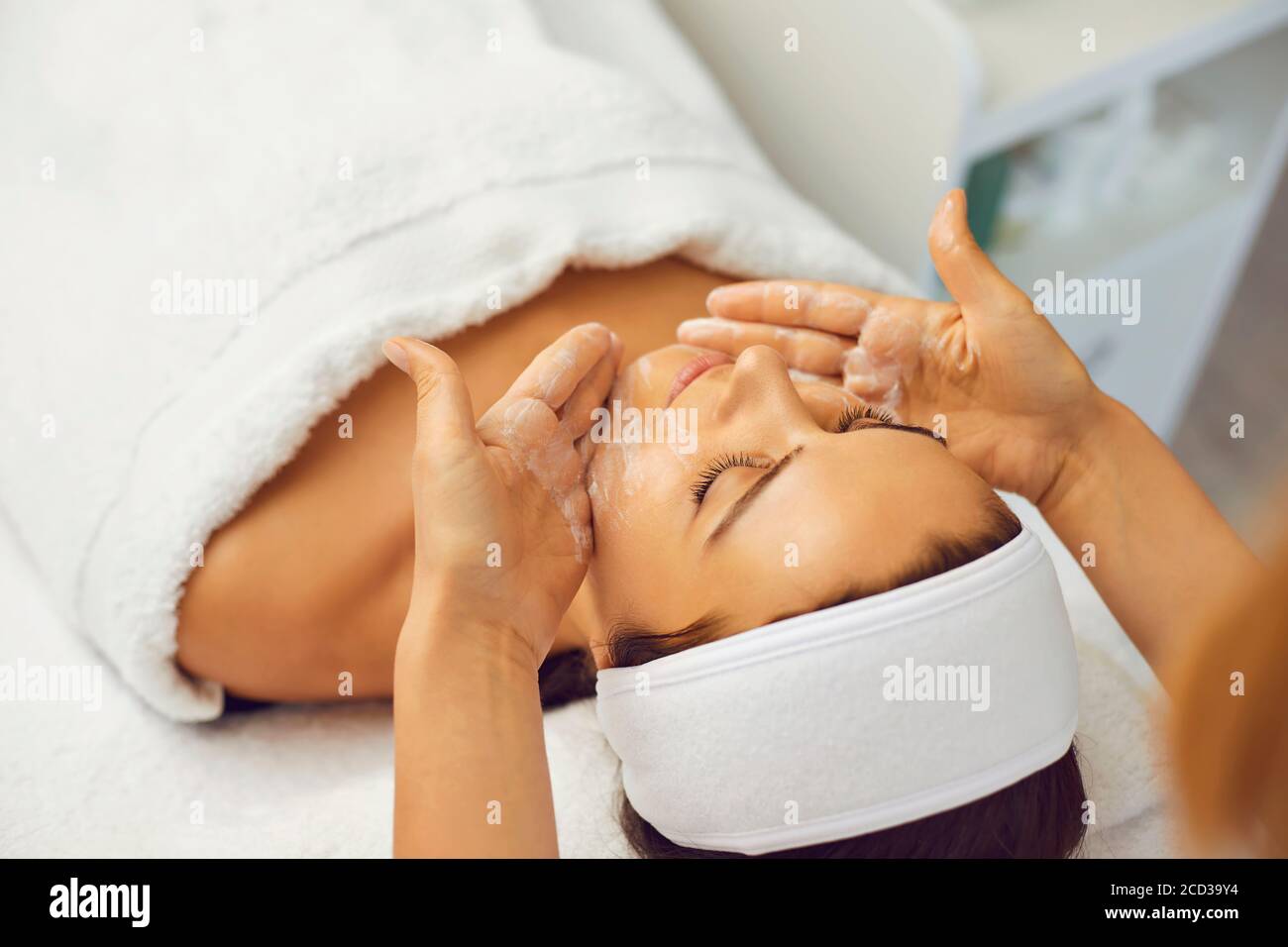 Woman beautician makes facial massage to woman patient in beauty salon Stock Photo