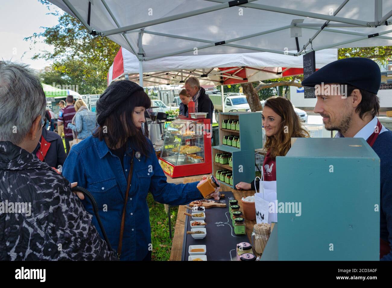 View of local market at Victor Harbour in South Australia as two tourist pay for and receive change for condiments purchased from two vendors. Stock Photo
