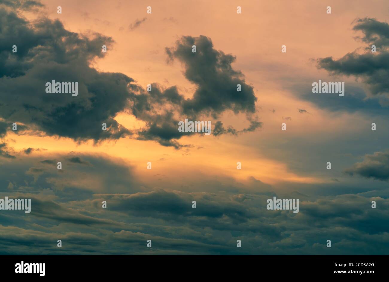 Sunset sky with gray and golden clouds. Gray sky and fluffy clouds. Thunder and storm sky. Sad and moody sky. Dead abstract background. Cloudscape. Stock Photo