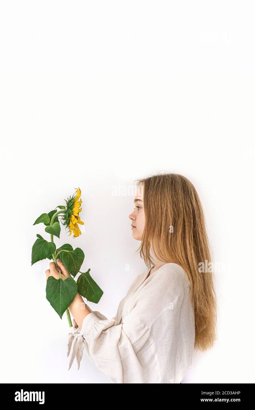 Beautiful young woman in linen dress holding sunflower on white background. Autumn concept. Stock Photo