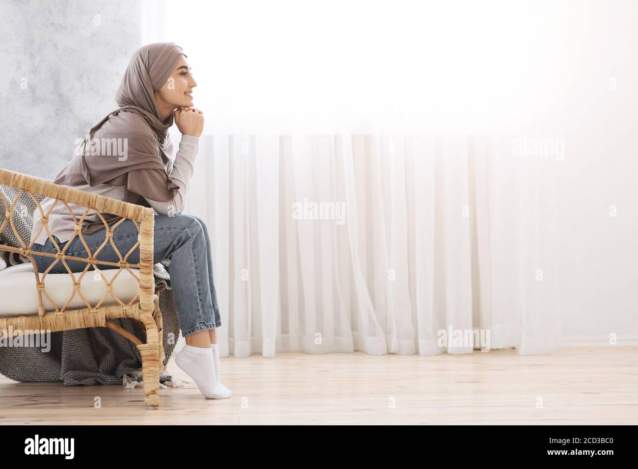 Pensive Muslim Girl In Hijab Relaxing In Wicker Chair At Home Stock ...