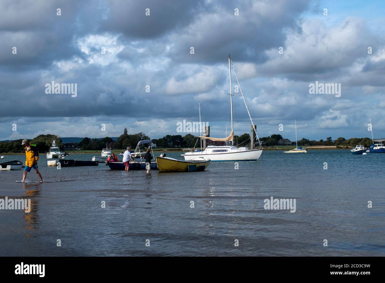 Itchenor Harbour on a beautiful summer day in England with people pulling their boat to shore. Stock Photo