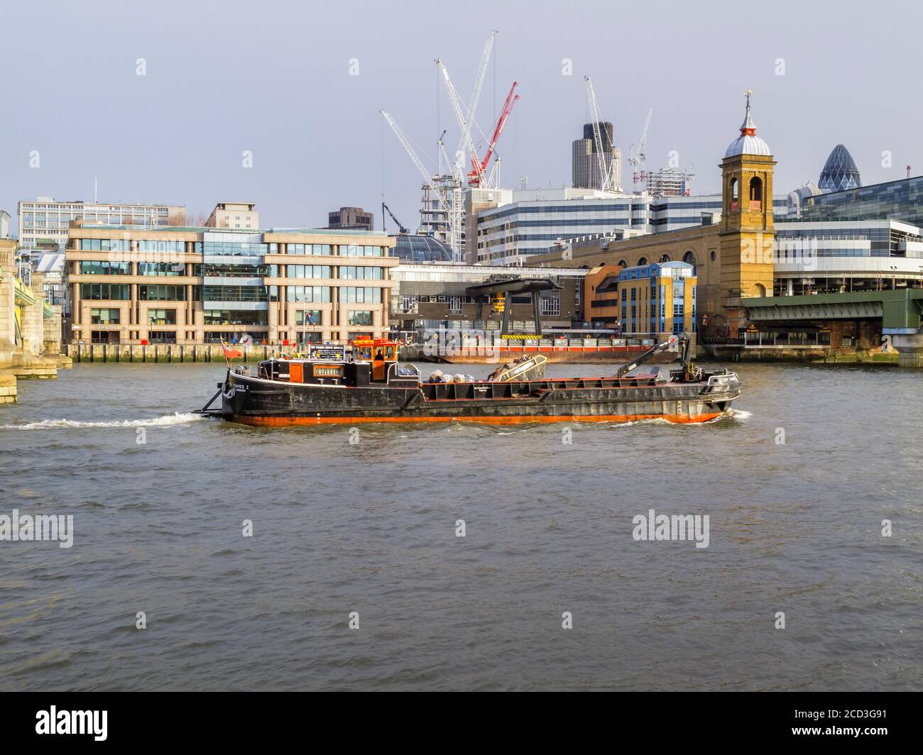 The refuse collection barge 'Tidy Thames 1' sails near the railway bridge over the River Thames at Cannon Street Station, City of London Stock Photo