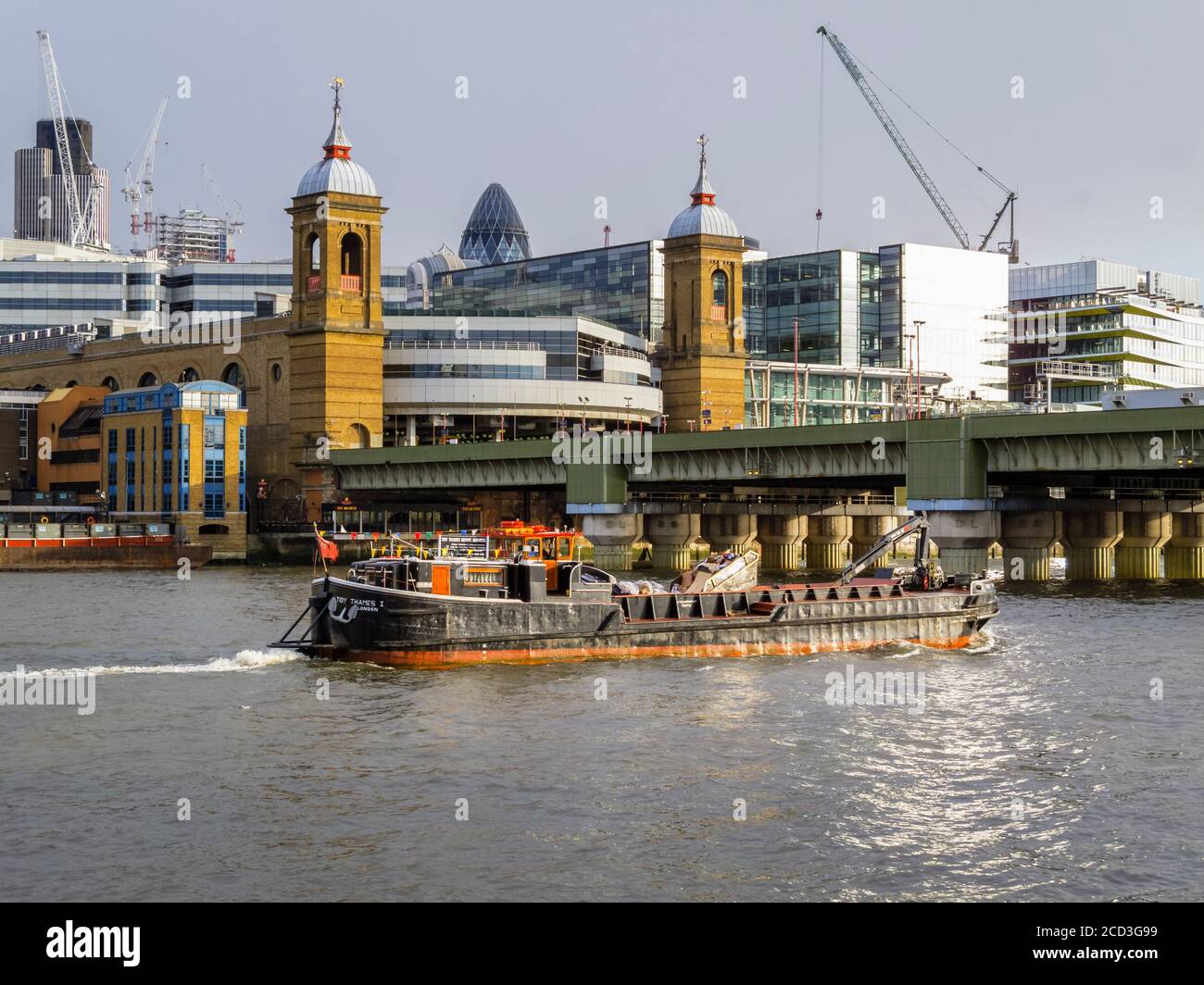 The refuse collection barge 'Tidy Thames 1' sails under the railway bridge over the River Thames at Cannon Street Station, City of London Stock Photo
